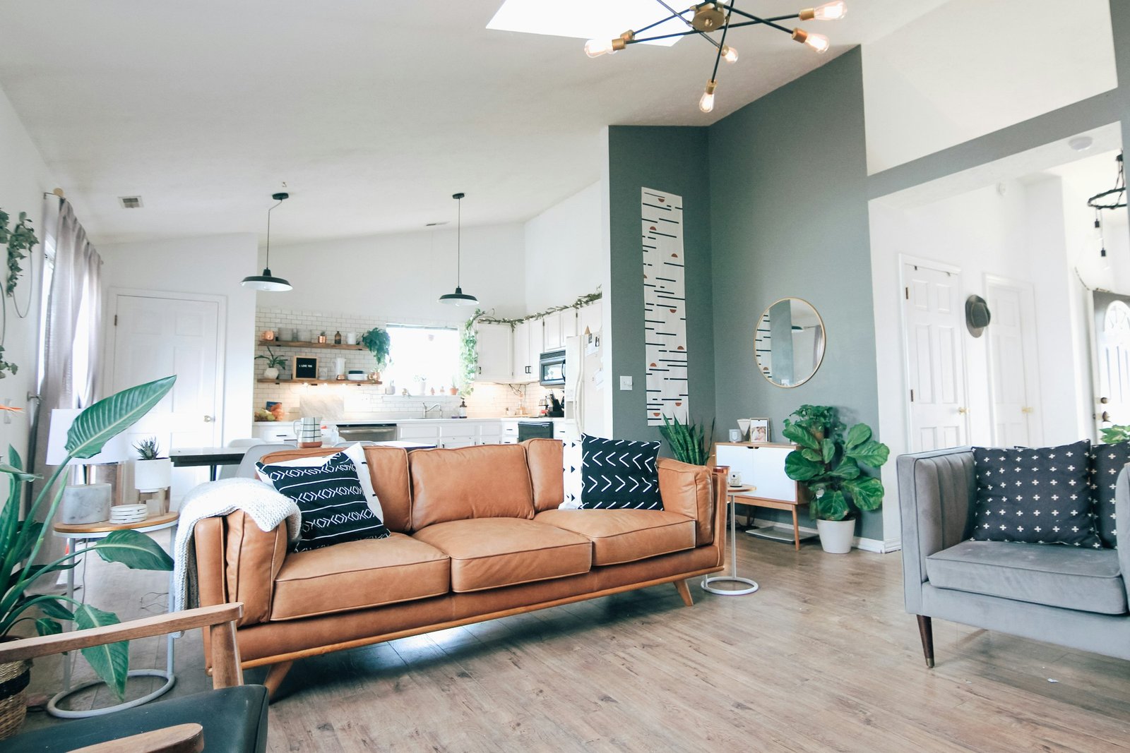An open plan apartment interior with a leather sofa and kitchen beyond